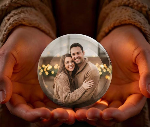 Hands holding a glowing video globe with a couple memory inside